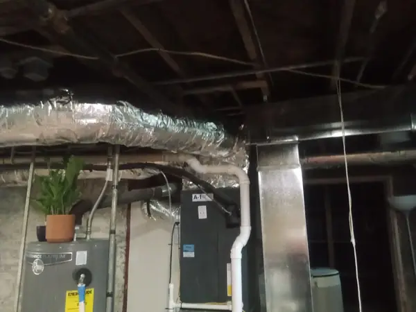 Insulated ductwork running along a basement ceiling
