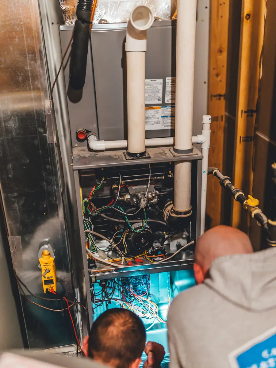 Two technicians installing and testing a furnace