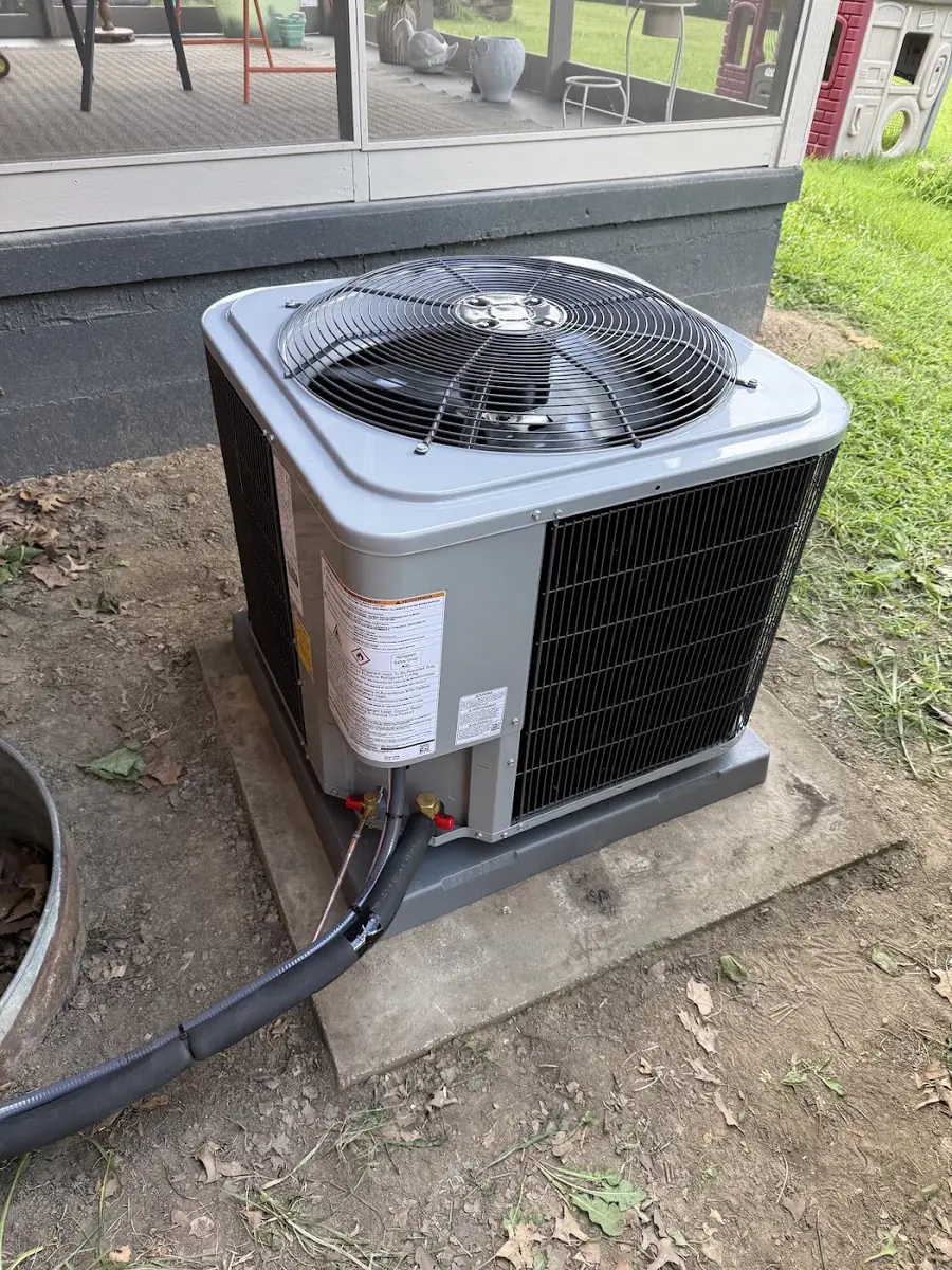 Freshly installed condenser on its pad beside a home